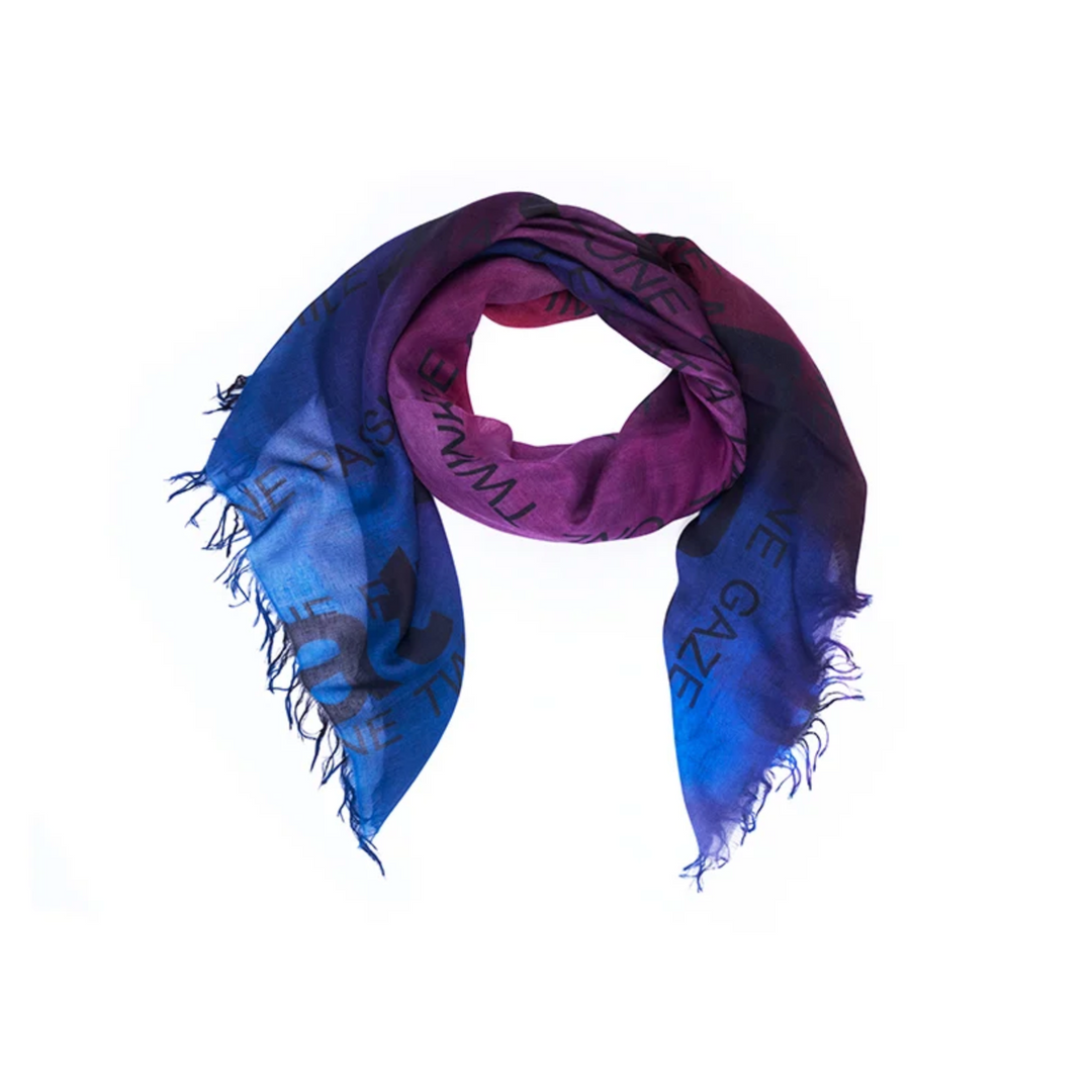 A lightweight square scarf with fringed edges, featuring a blue-to-purple gradient and black graphic text, shown on a plain white background.