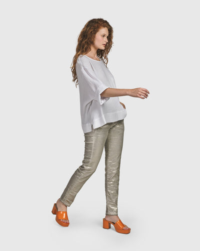 A woman in ALEMBIKA's Iconic Stretch Jeans and a white top, rocking ALEMBIKA's orange heels.