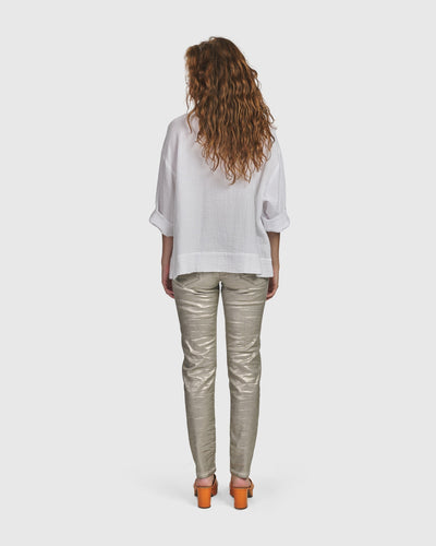 The back view of a woman wearing an ALEMBIKA white shirt and ALEMBIKA Iconic Stretch Jeans with a metallic luster and ultra-soft feel.