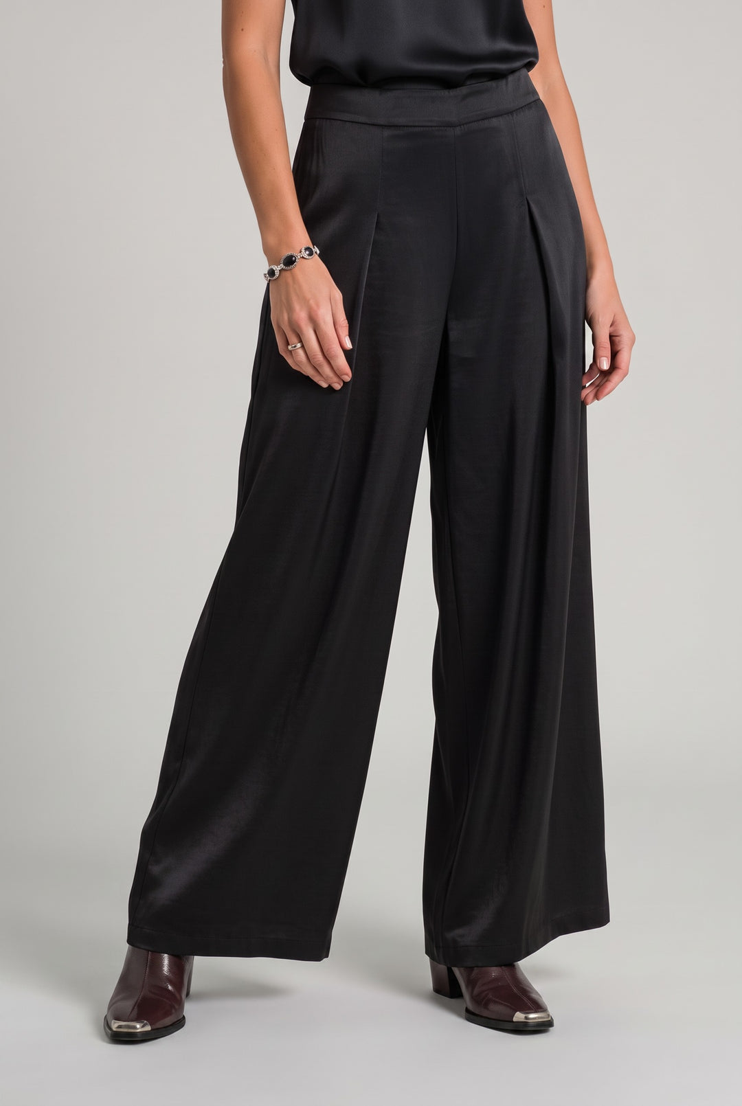 Model wearing Just Perfect Collection Online black sateen single pleat wide-leg trousers with dark leather boots