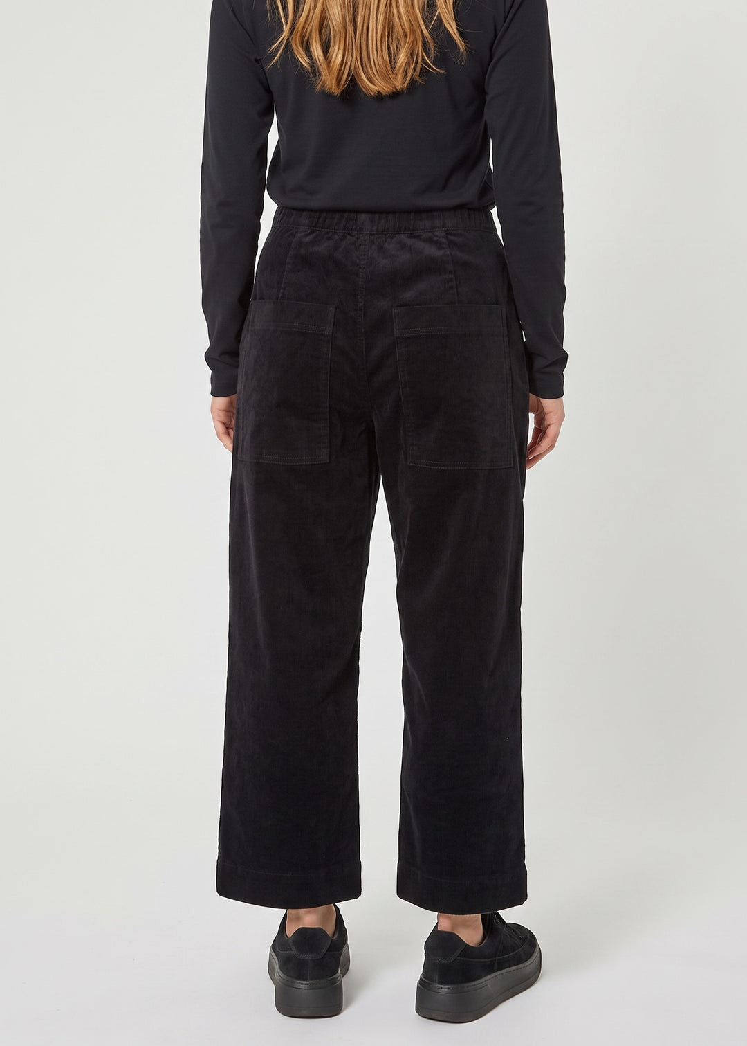 Just Perfect Collection Online black velvet trousers with a flat front and back pockets, worn by a woman from behind.