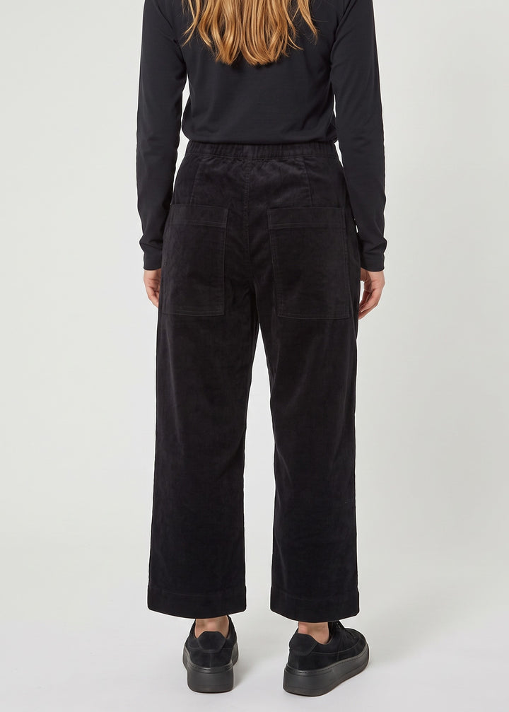 Just Perfect Collection Online black velvet trousers with a flat front and back pockets, worn by a woman from behind.