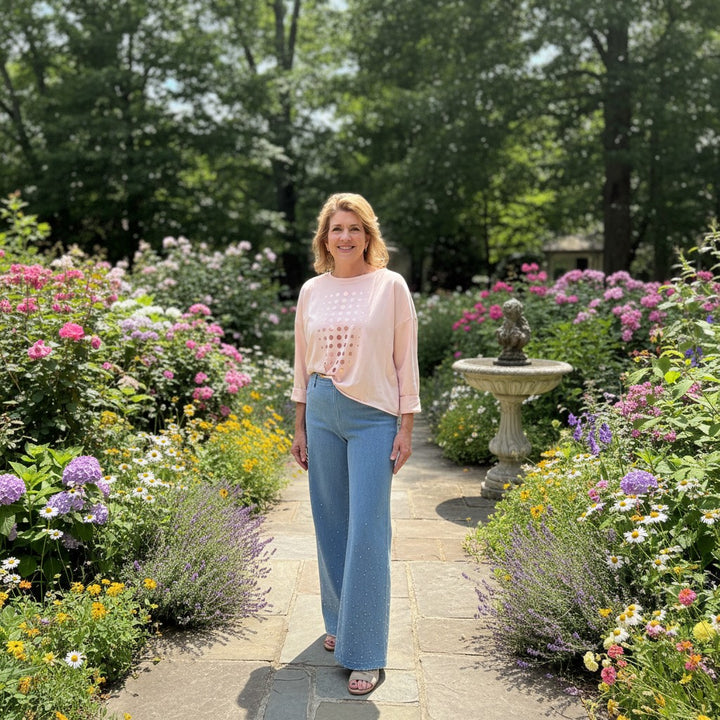 Woman wearing a Just Perfect Collection Online blush gold Pima cotton boxy tee with metallic shimmer in a garden.