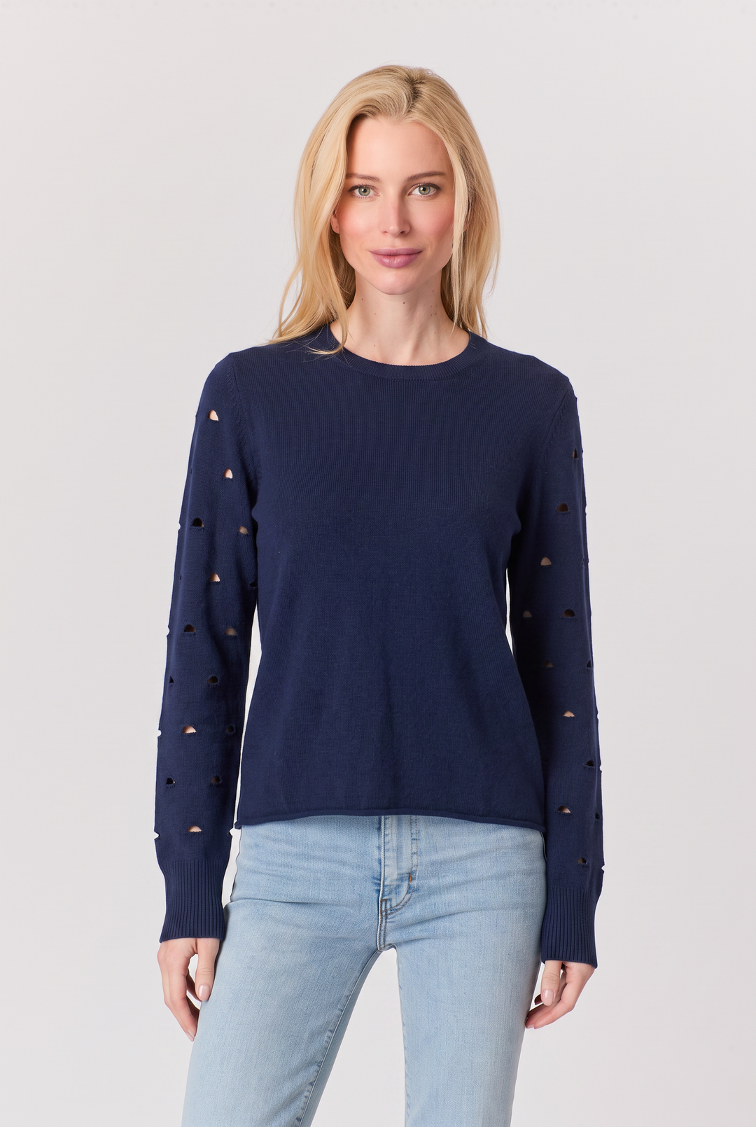 Just Perfect Collection Online navy sweater with perforated sleeves worn by a blonde model with light blue jeans