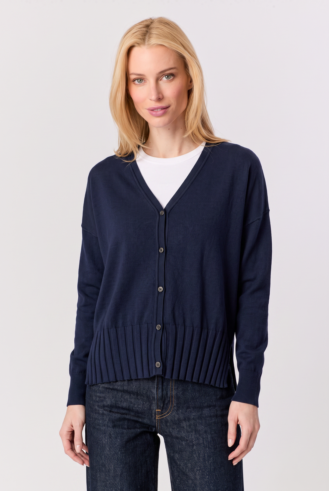 Model wearing a Just Perfect Collection Online navy V-neck cardigan with a ribbed hem over a white t-shirt