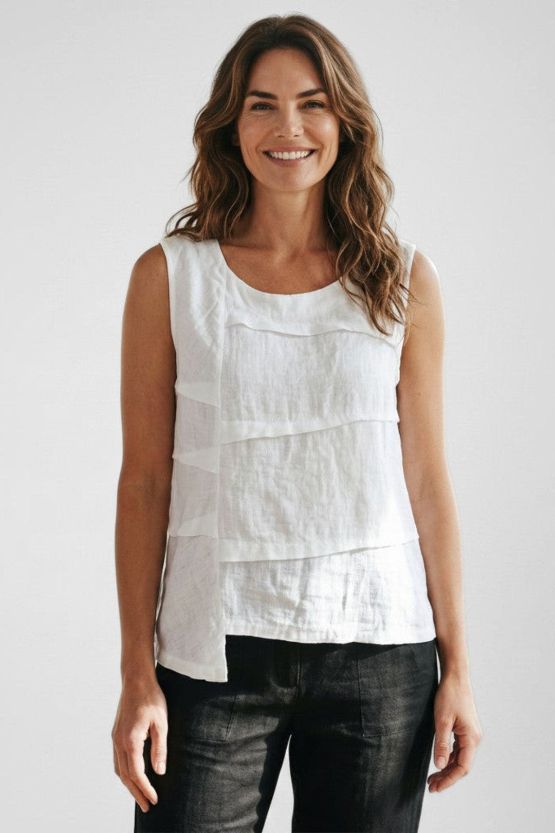Model wearing a Just Perfect Collection Online white linen sleeveless tuck top with an asymmetric hemline.