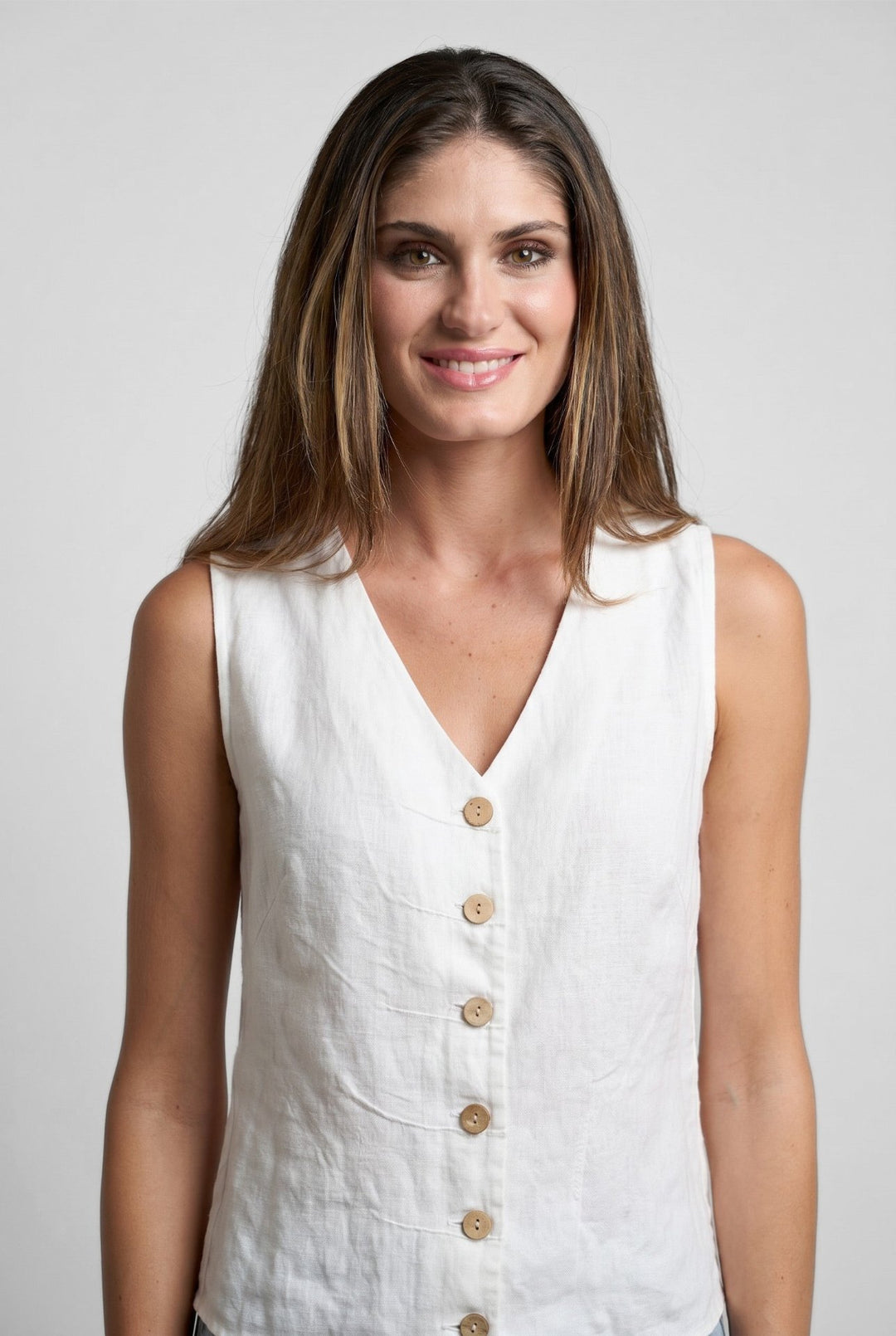 Woman wearing a Just Perfect Collection Online white linen tuck vest with button-front detail against a grey background